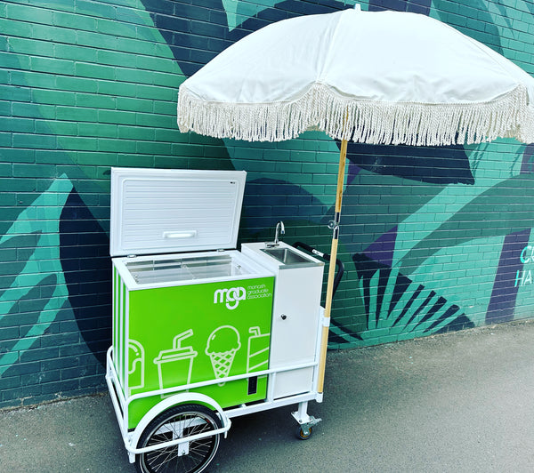 Fun ice cream cart featuring a green design and parasol, supplied by PromoWheels, ready to serve tasty treats at events and gatherings.
