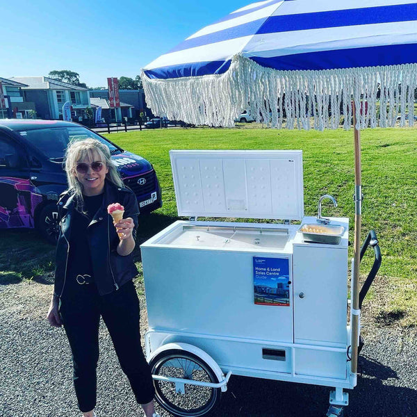 Joyful scene of a woman enjoying an ice cream cone by a mobile cart, supplied by PromoWheels, showcasing how to elevate any event with delicious treats.
